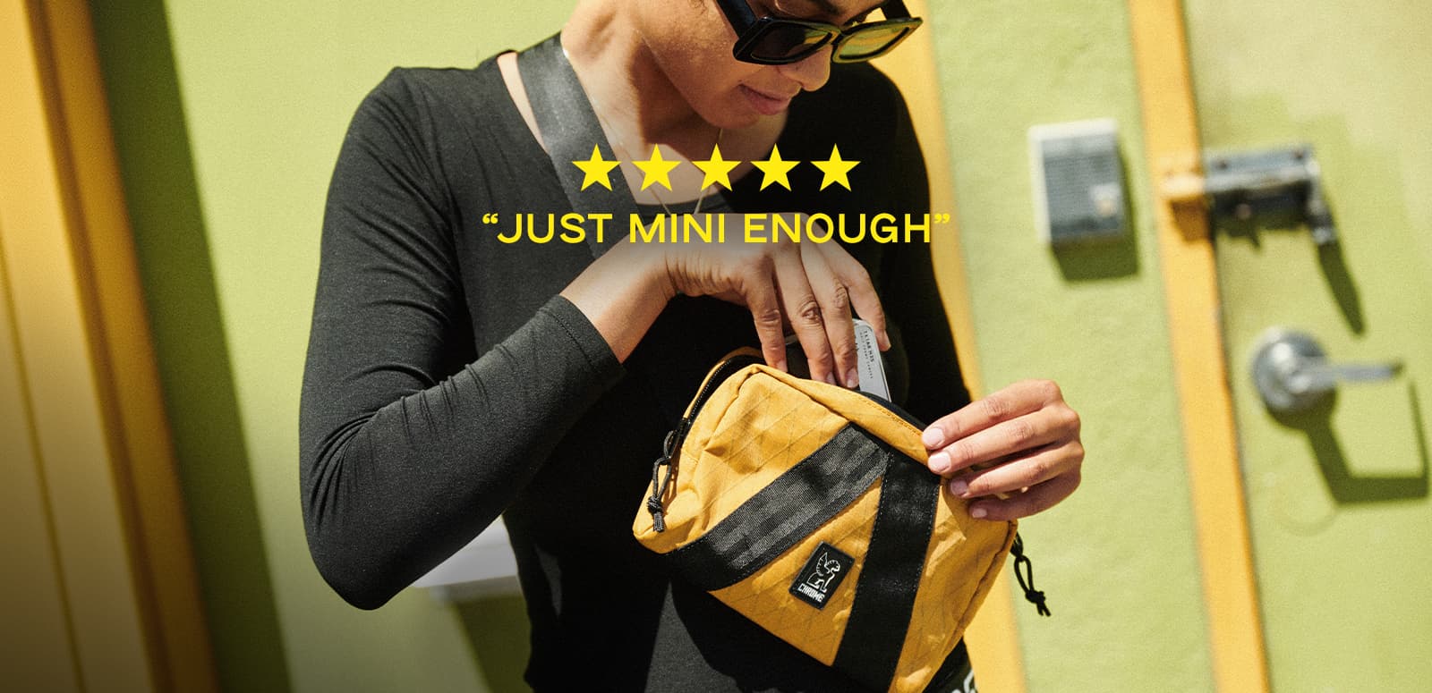 Woman putting her phone into a Mini Tensile sling bag